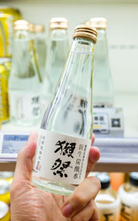 a person holding a bottle of sake in a store