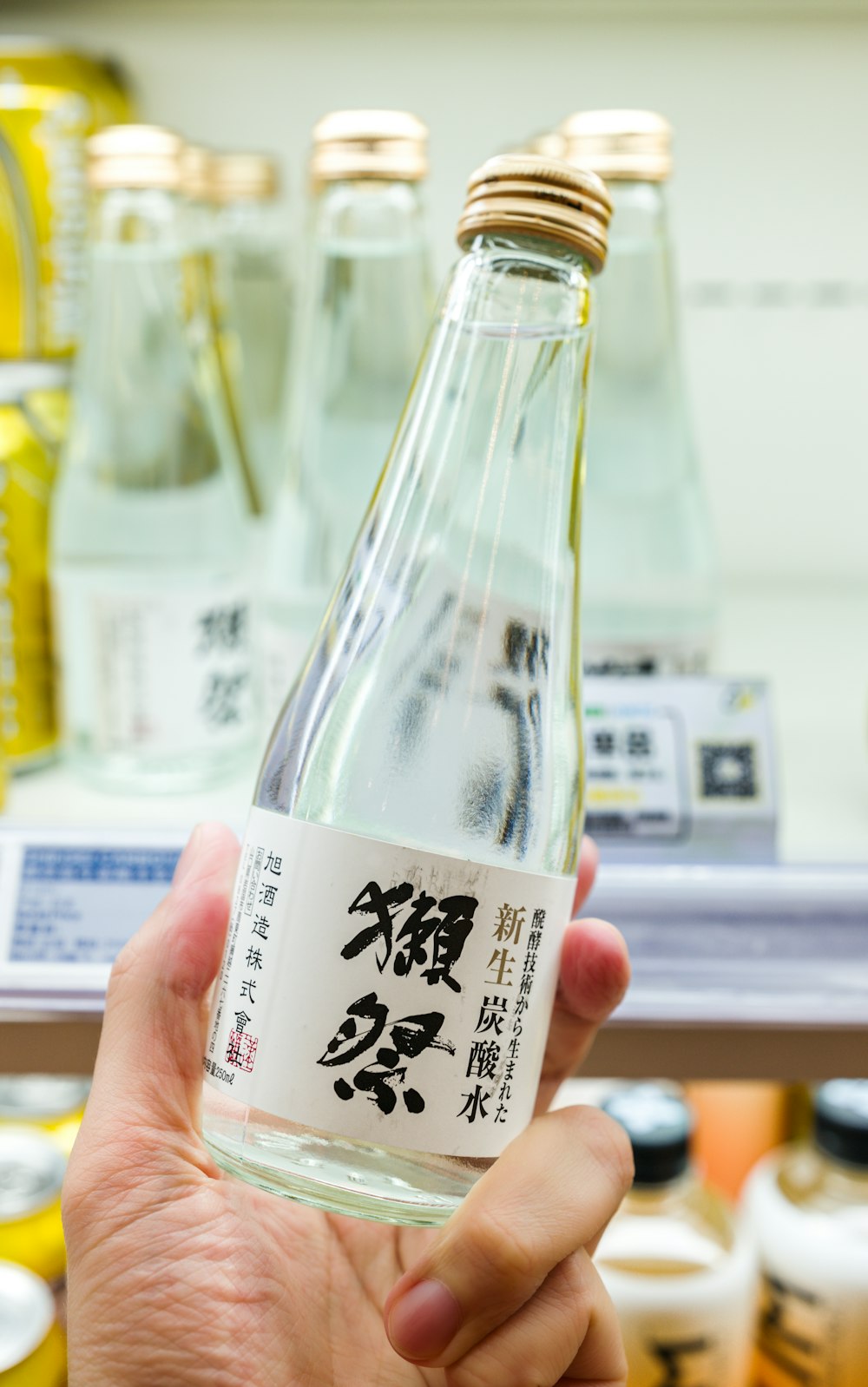 a person holding a bottle of sake in a store