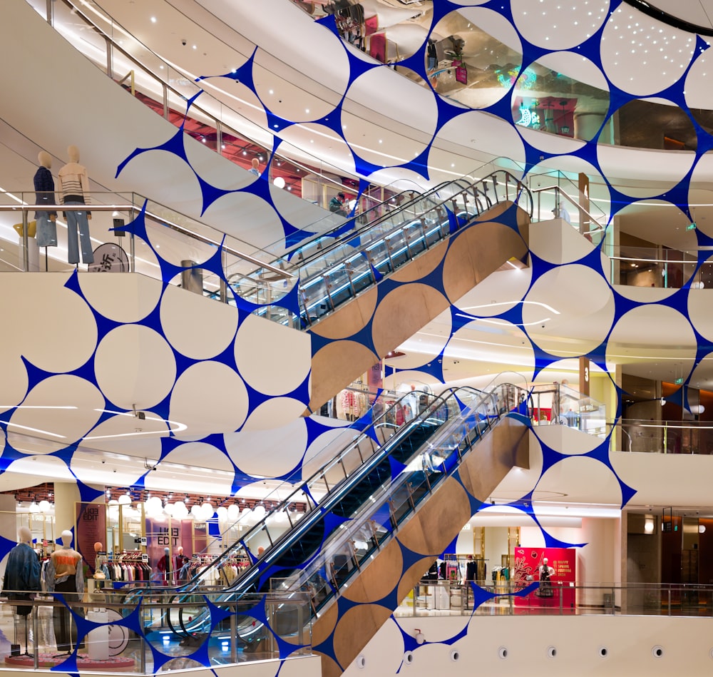 an escalator in a shopping mall with blue and white circles on the wall