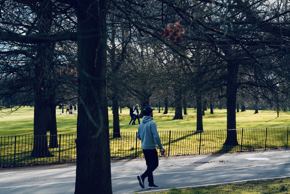 a man walking down a sidewalk in a park