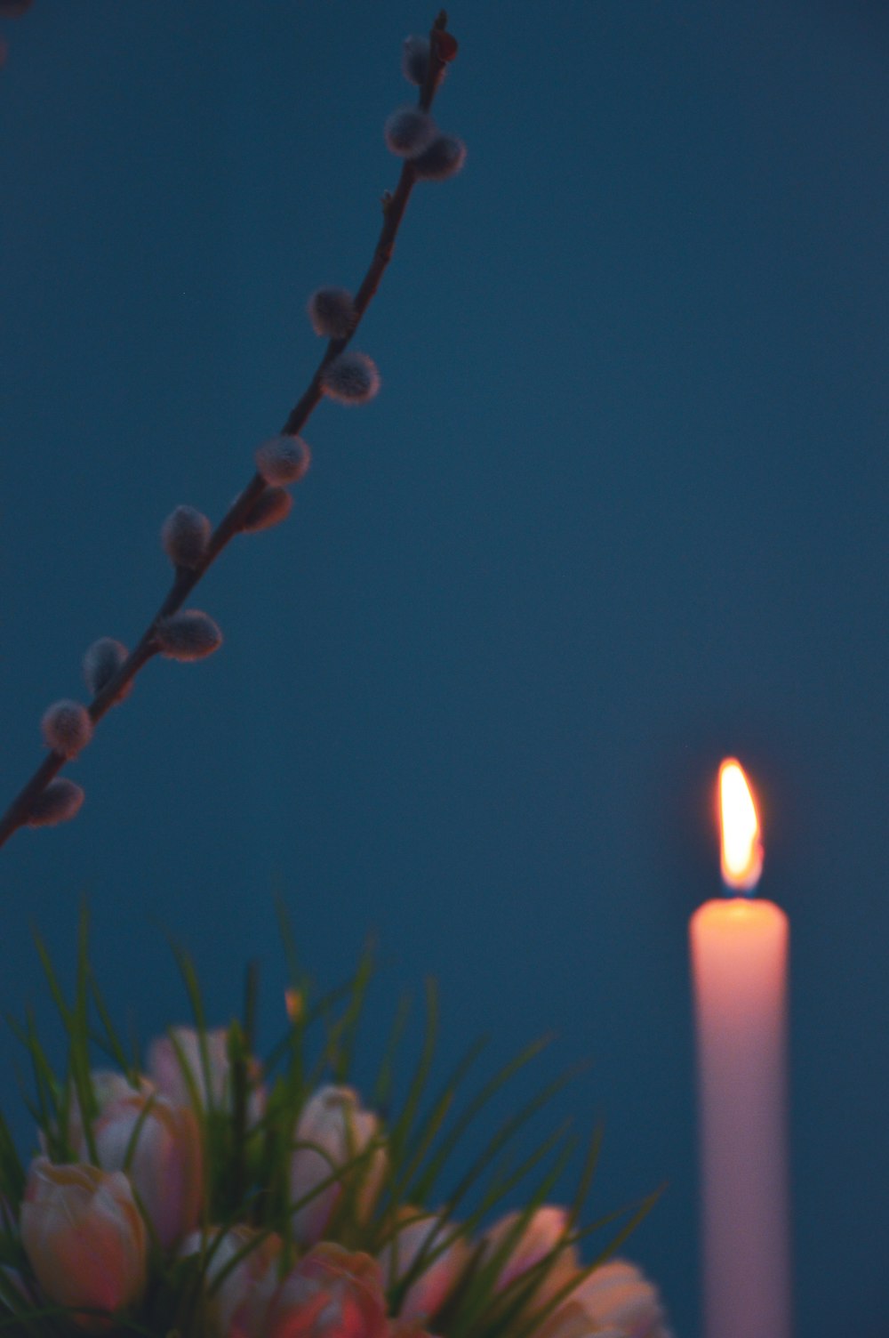 a lit candle sitting next to a bouquet of flowers