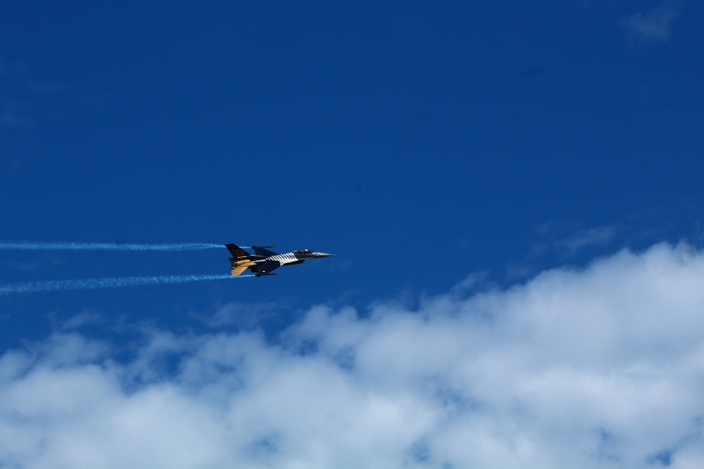 a fighter jet flying through a blue cloudy sky