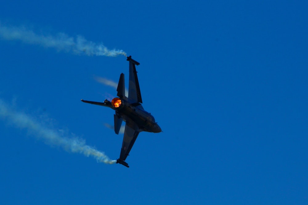 a fighter jet flying through a blue sky