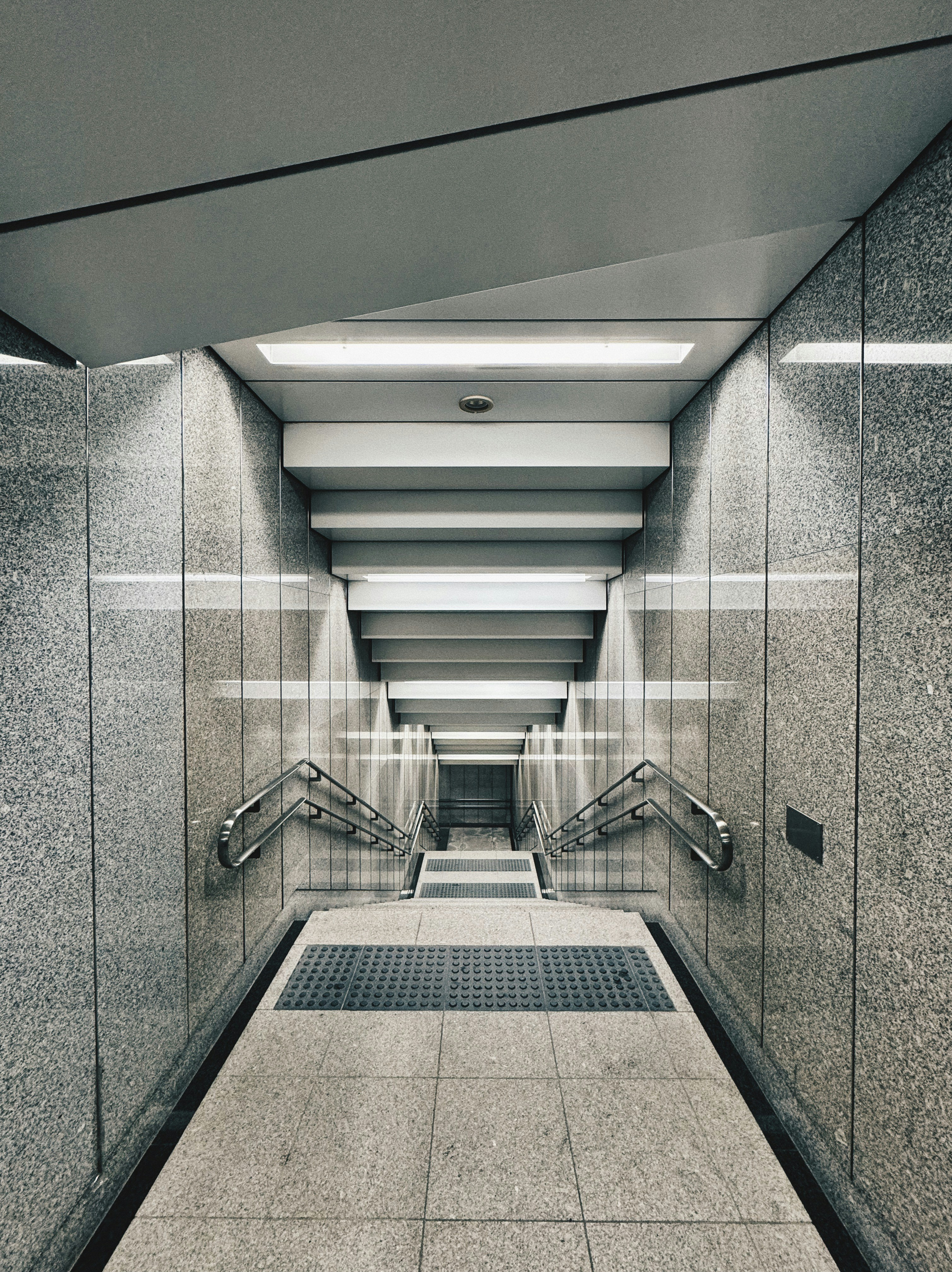 ein langer Flur mit Fliesenboden und Handläufen aus Metall