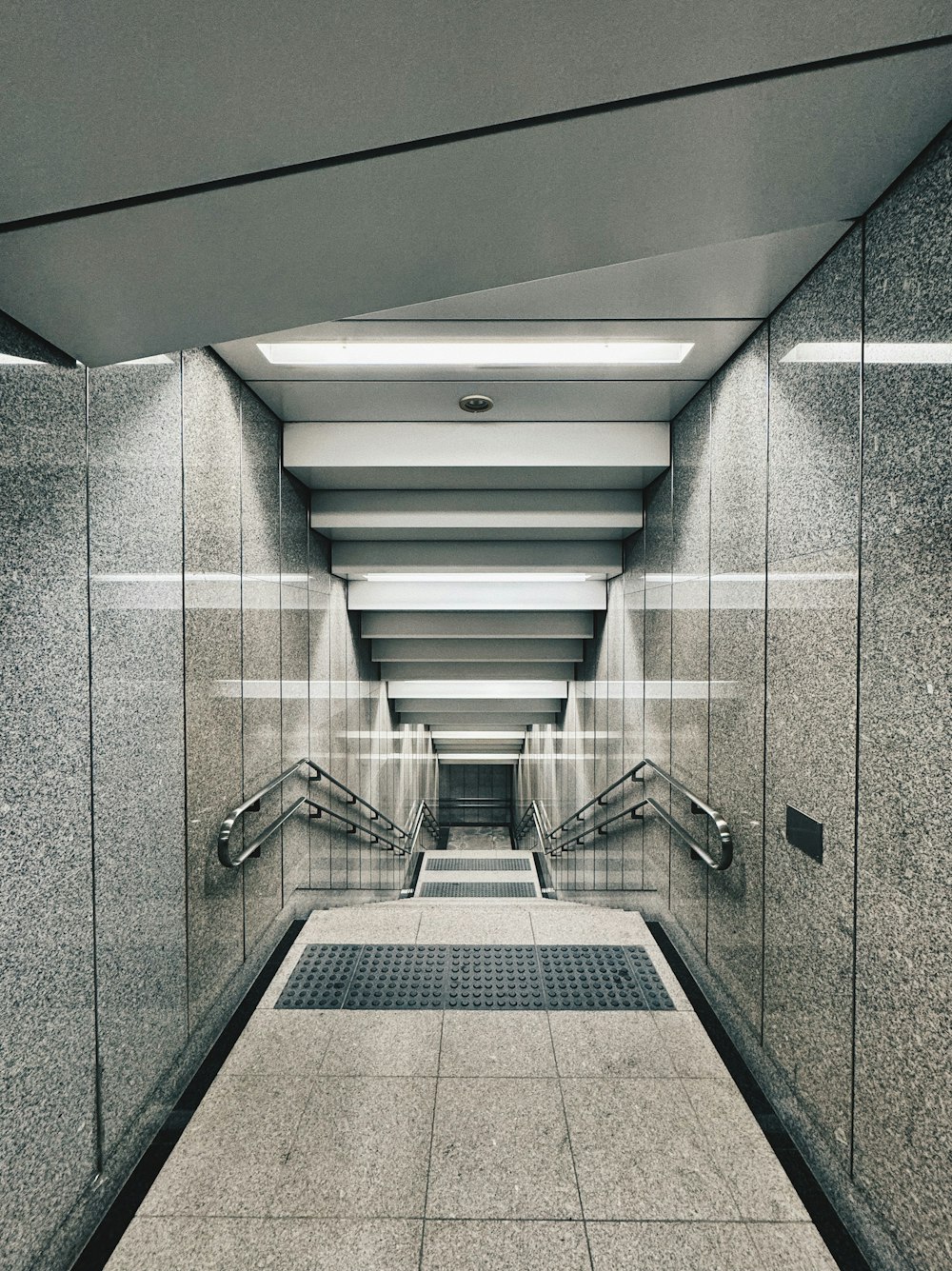 a long hallway with a tiled floor and metal handrails