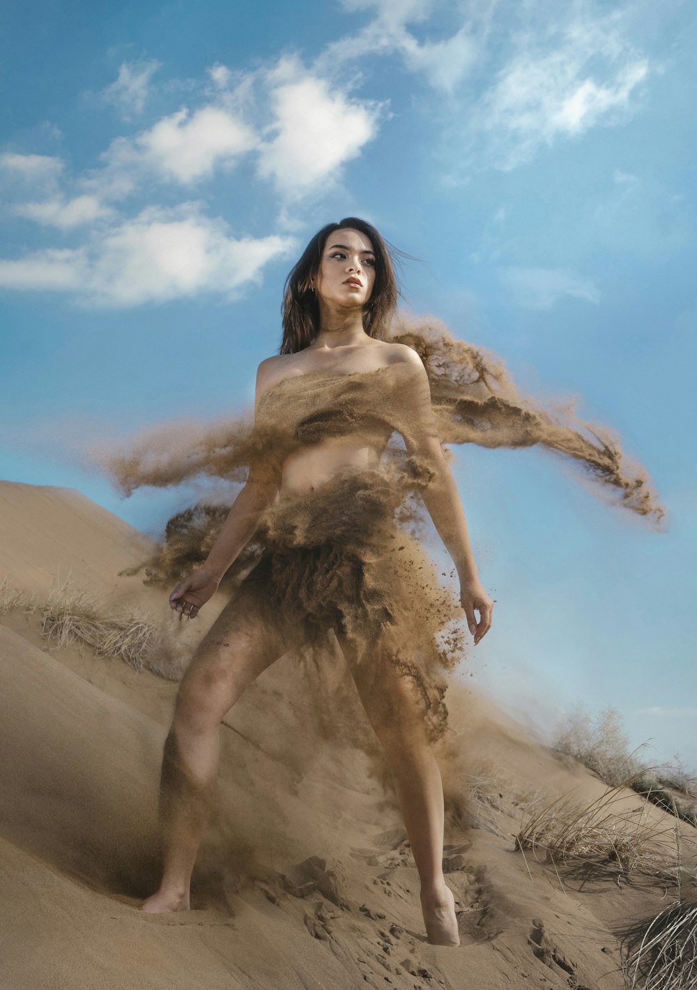 a woman standing on top of a sandy hill