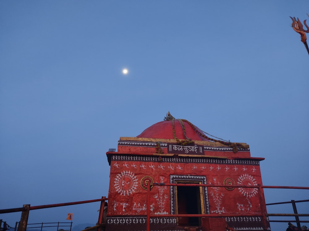 a red building with a moon in the sky