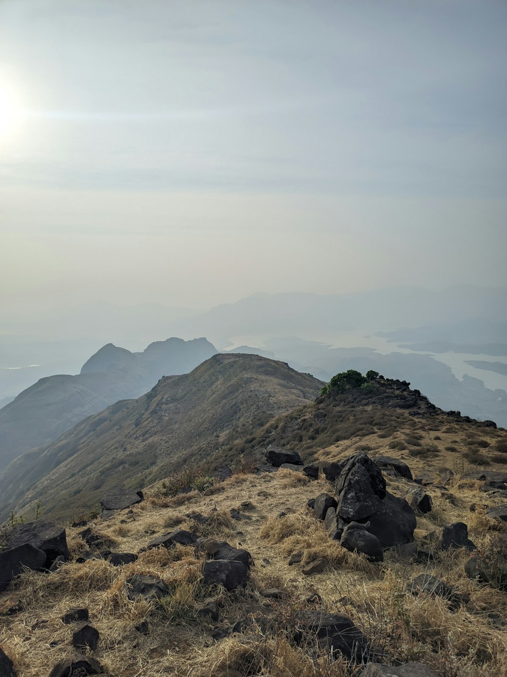 a view of a mountain range with rocks and grass in the foreground