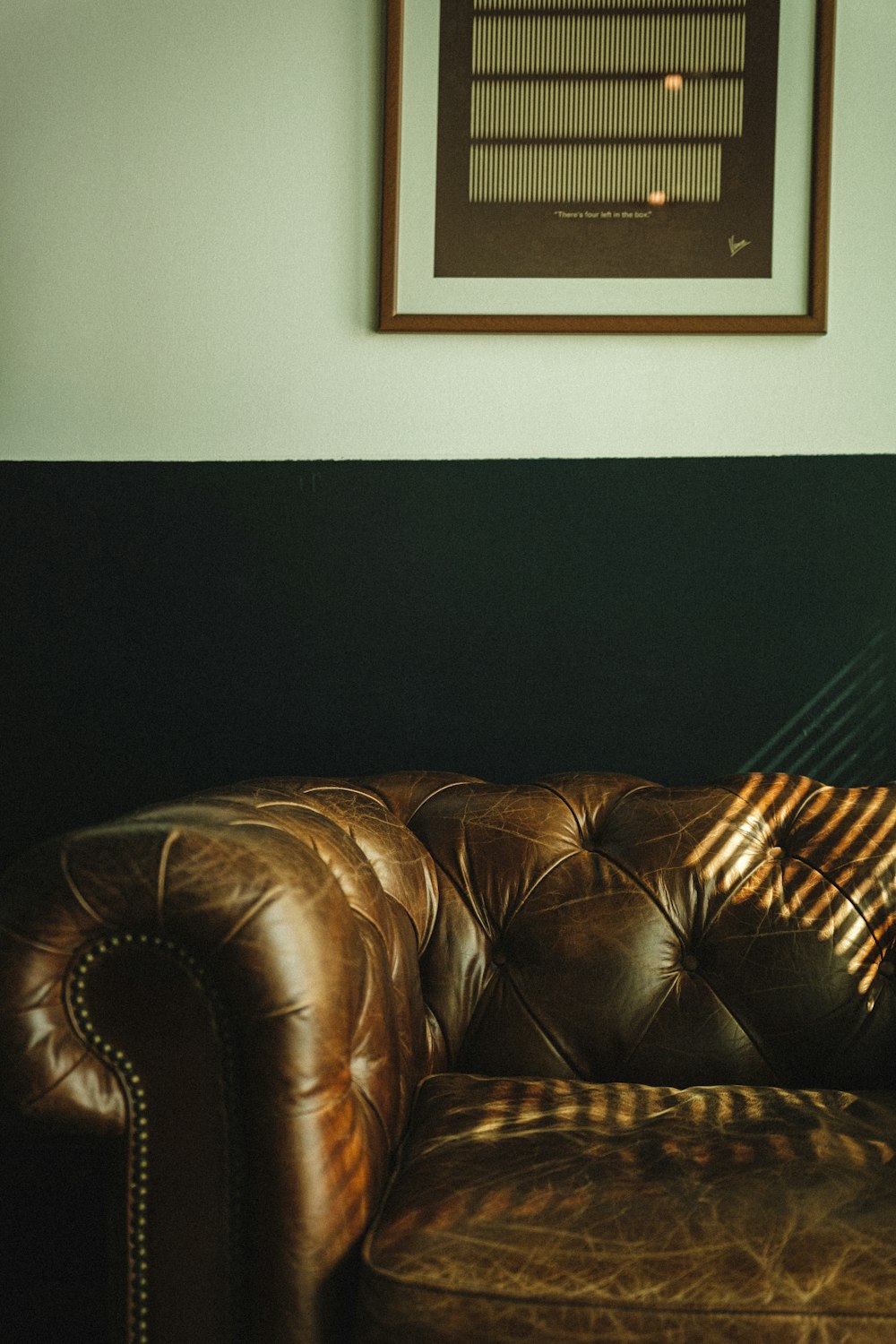 a brown leather couch sitting in a living room next to a window