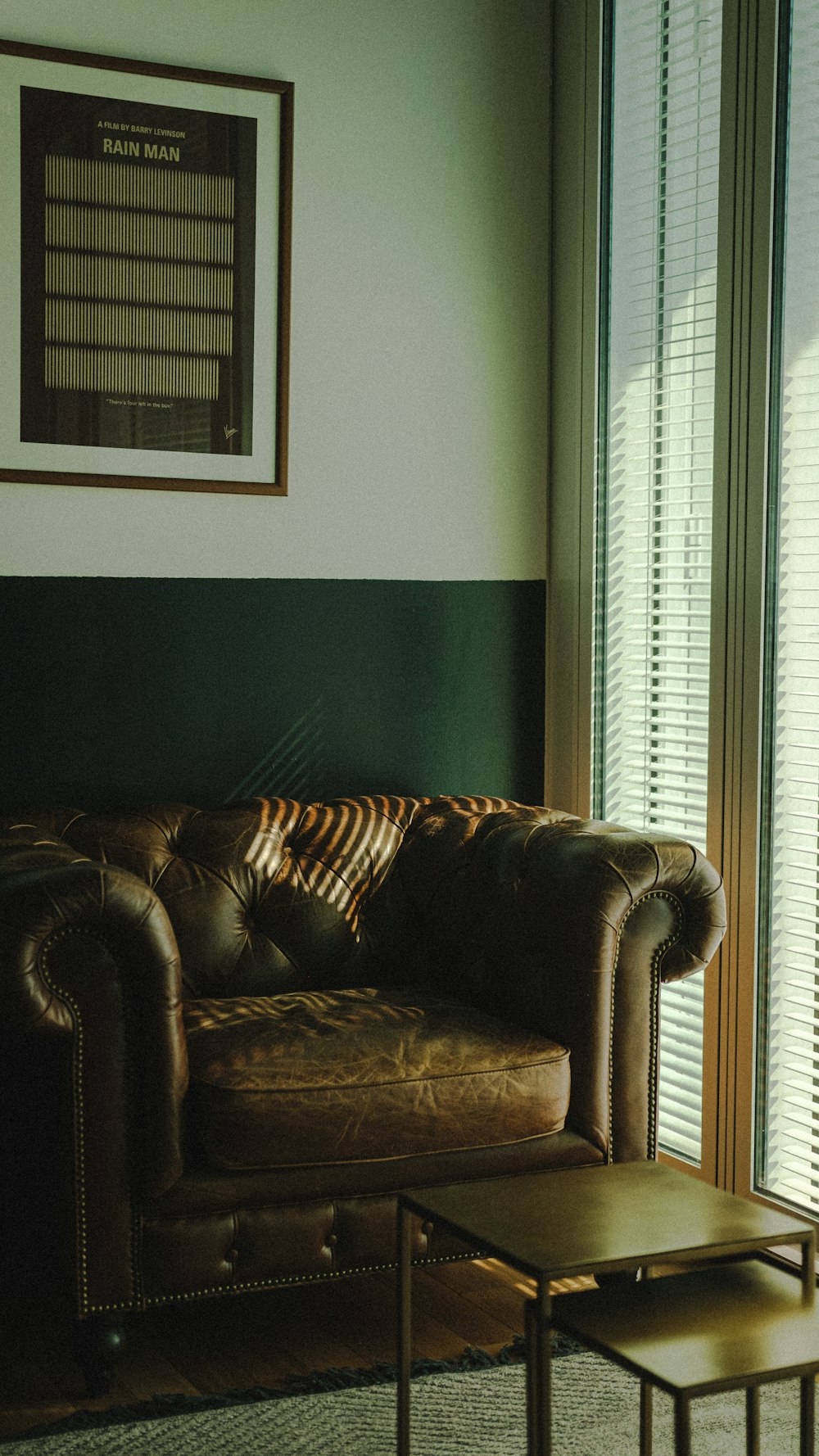 a brown leather couch sitting in a living room next to a window