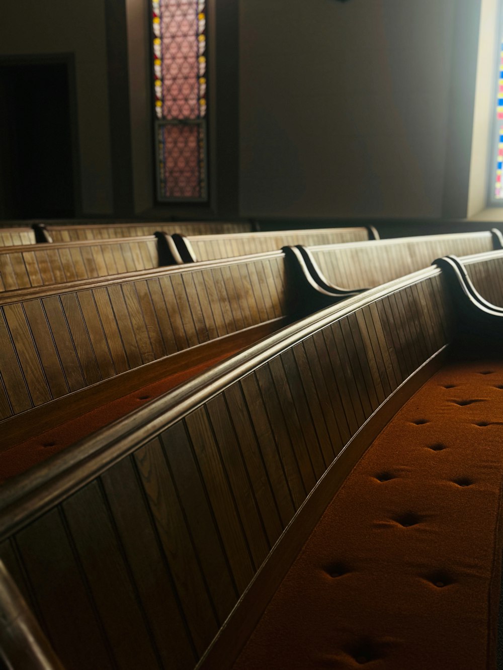 a row of pews in a church with stained glass windows