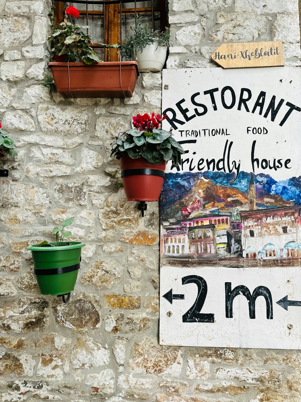 Un letrero de restaurante en una pared de piedra con plantas en macetas