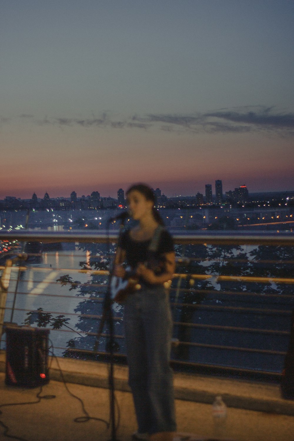 a woman singing into a microphone while standing on a balcony