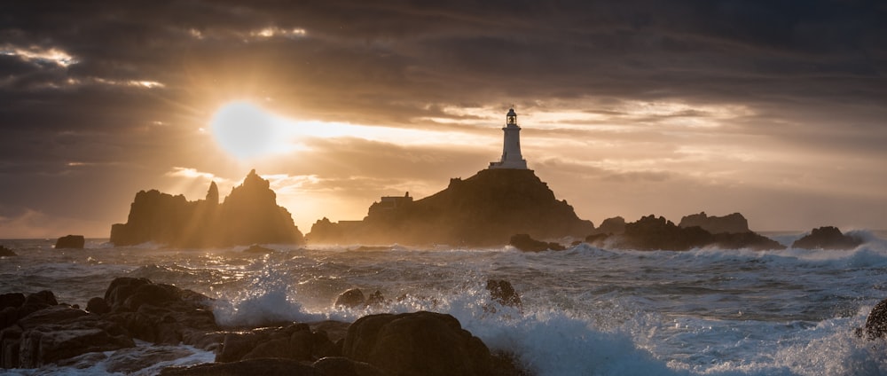 a lighthouse on a rocky shore at sunset