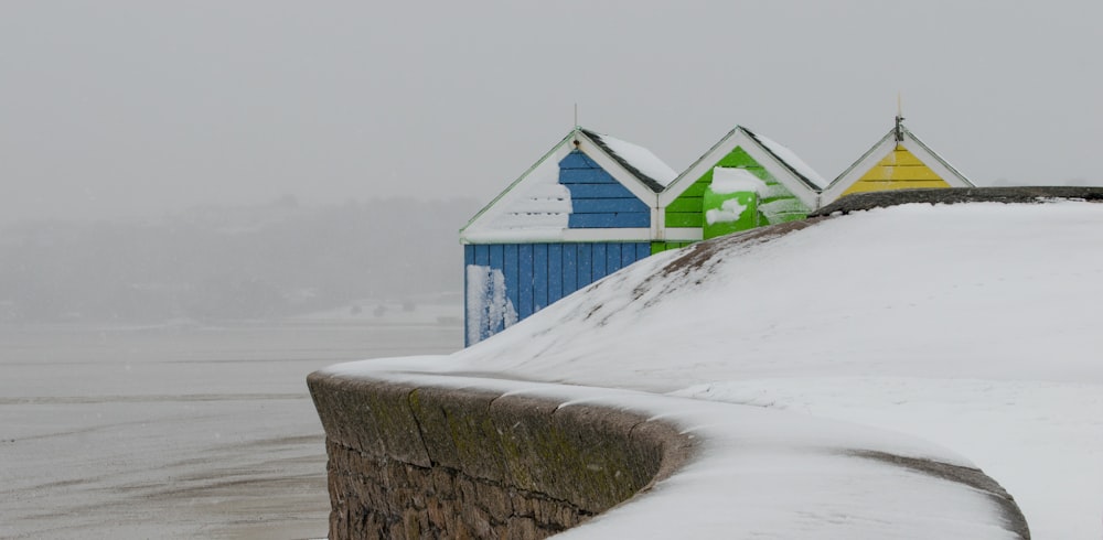 eine Reihe bunter Strandhütten, die mit Schnee bedeckt sind