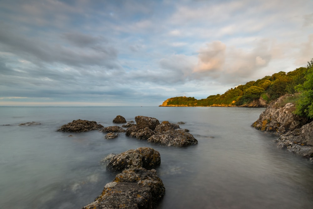 a body of water surrounded by rocks under a cloudy sky