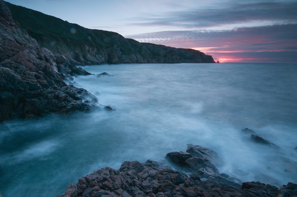 a long exposure photo of the ocean at sunset