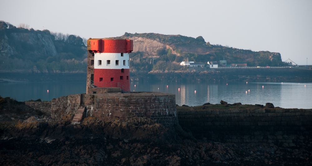 a red and white lighthouse sitting on top of a rock