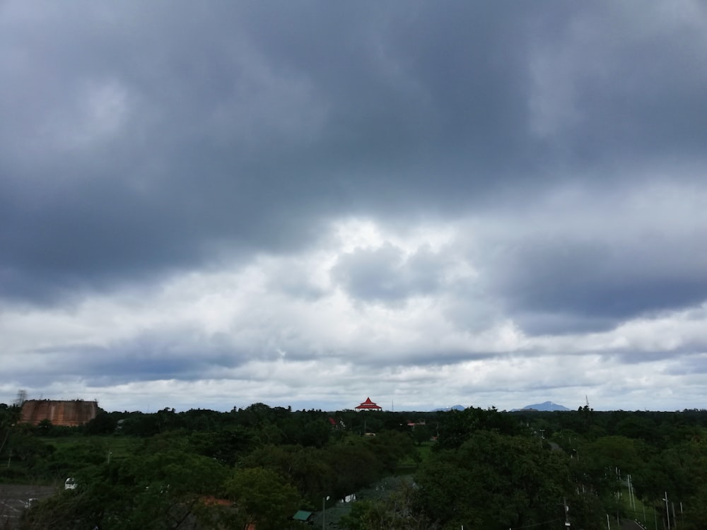 a view of a cloudy sky over a forest