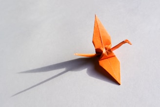 an orange origami bird on a white surface