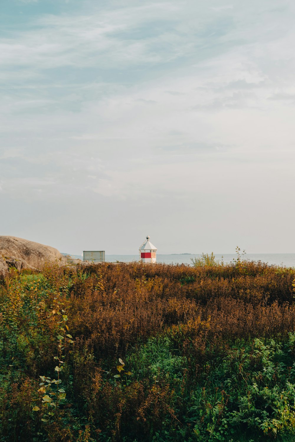 a red and white lighthouse sitting on top of a lush green field