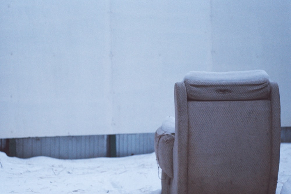 une chaise assise dans la neige à côté d’un bâtiment