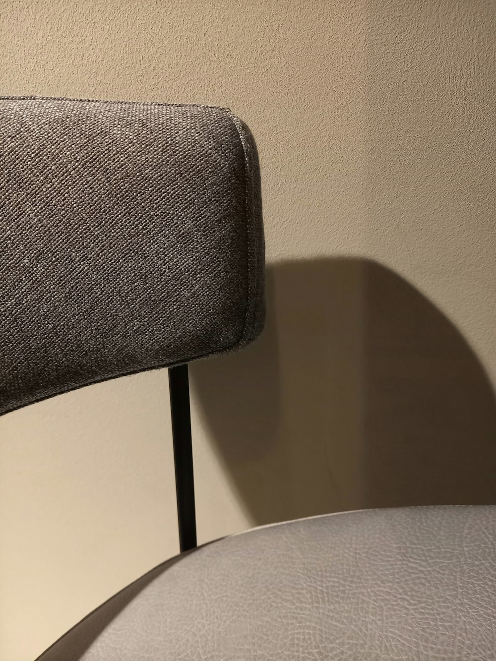 a close up of a chair with a shadow on the wall