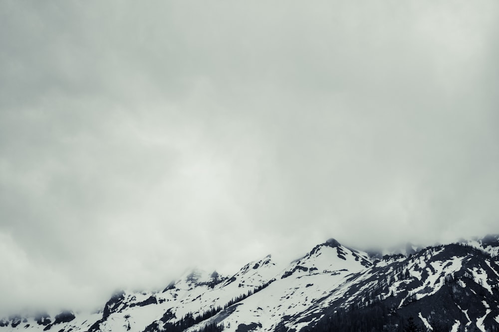 a mountain covered in snow under a cloudy sky