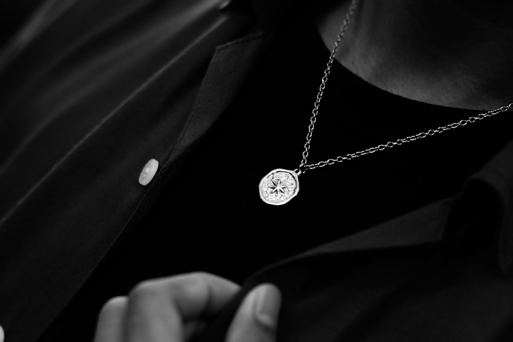 a person wearing a necklace with a diamond on it