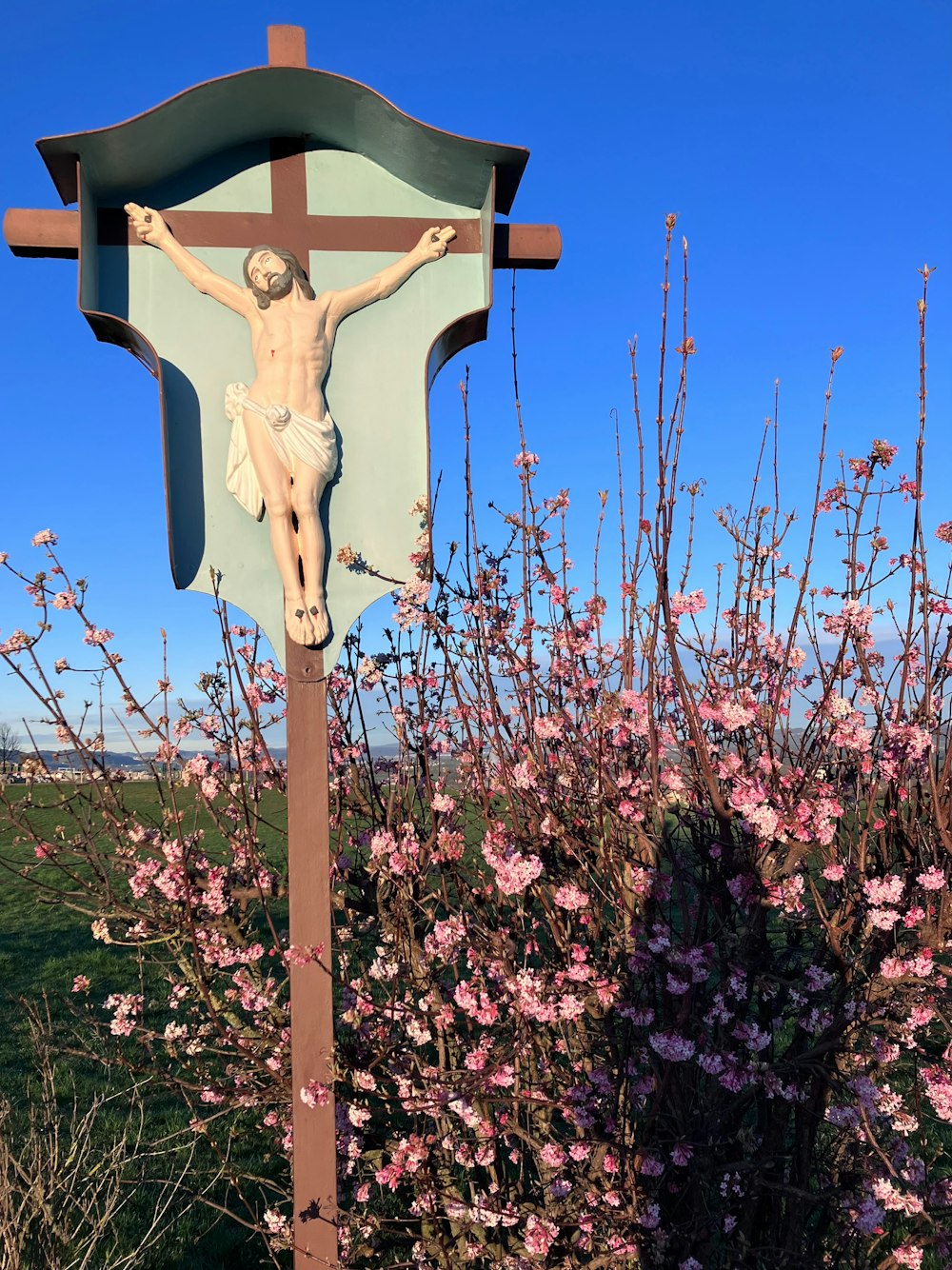 a wooden crucifix with flowers in the background