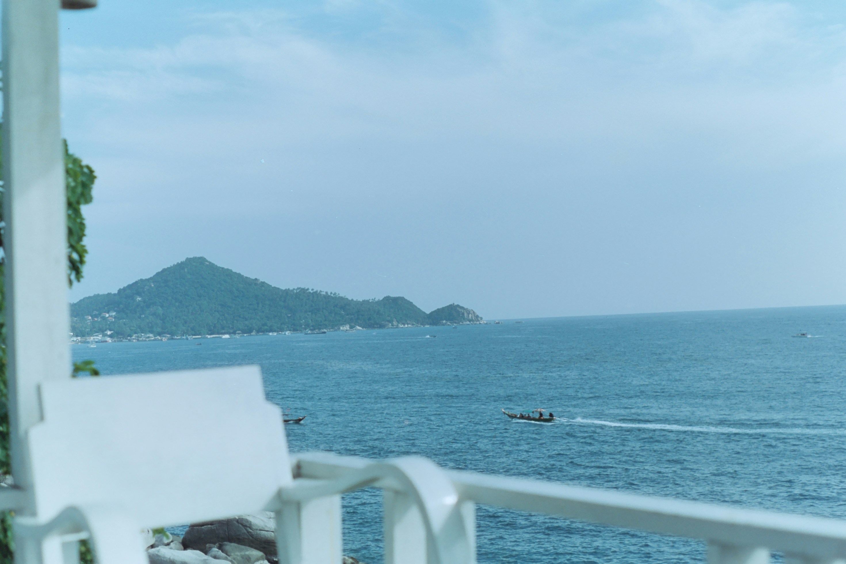 a white chair sitting on top of a balcony next to the ocean