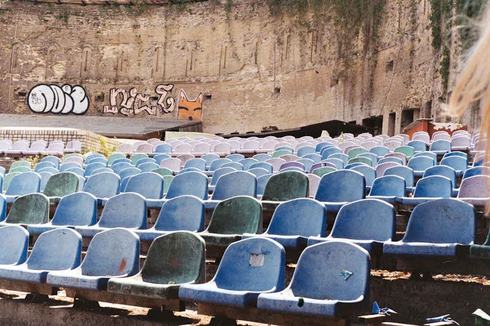 a row of blue chairs sitting in front of a graffiti covered wall