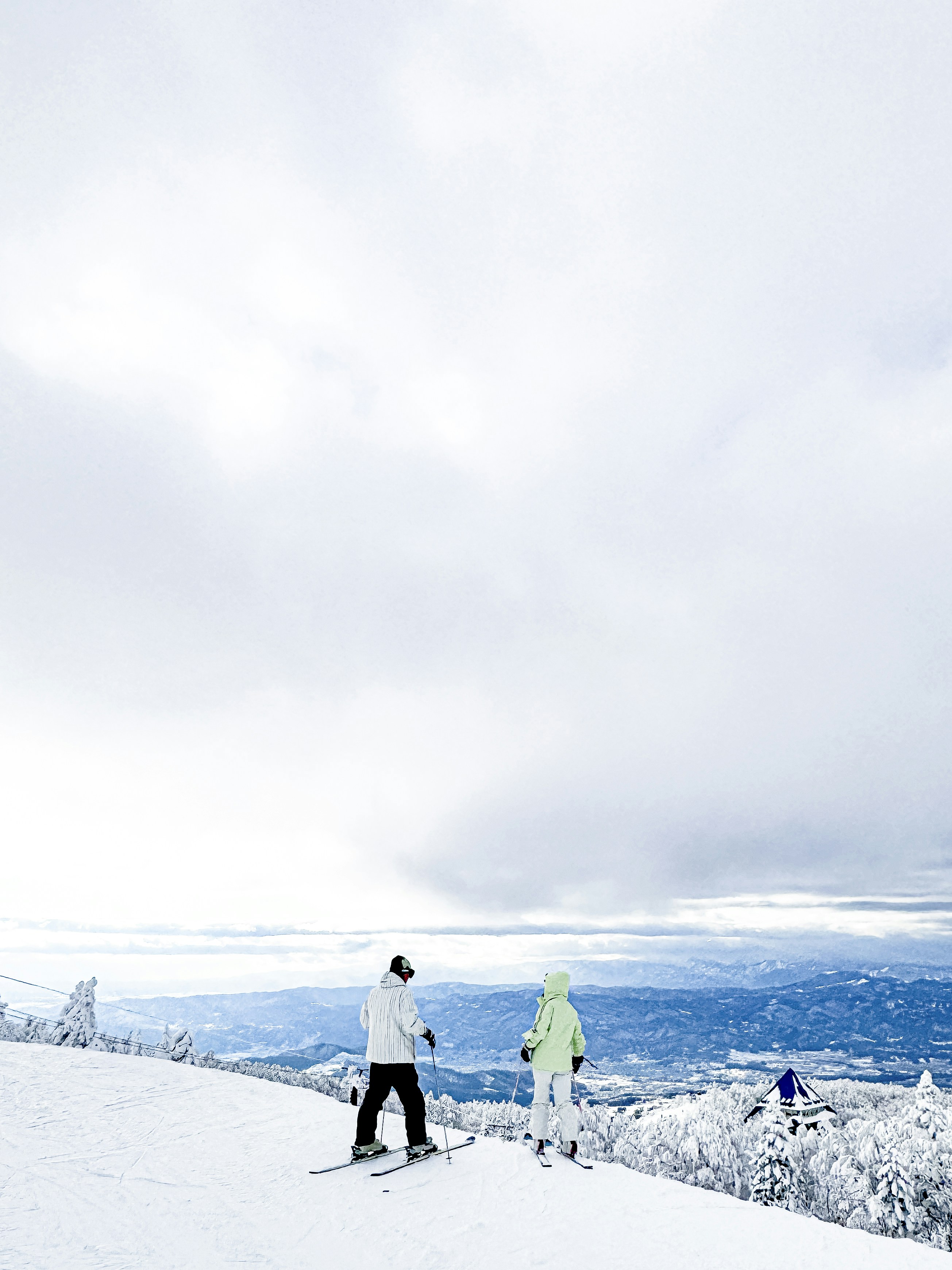 a couple of people riding skis on top of a snow covered slope