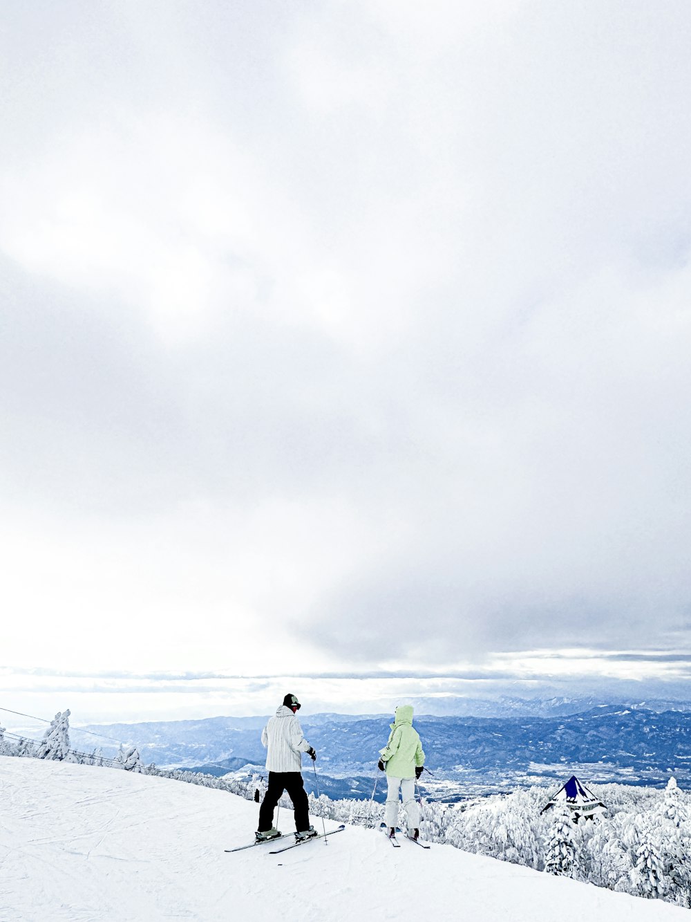 a couple of people riding skis on top of a snow covered slope