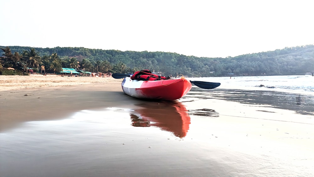 a red and white boat sitting on top of a beach