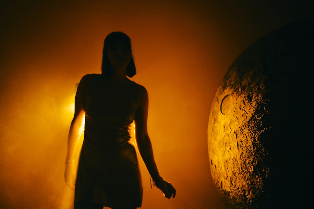 a woman standing next to a large object in the dark