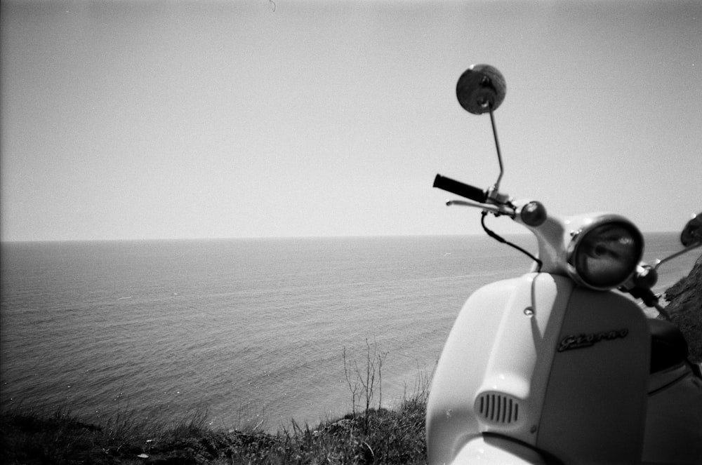 a scooter parked on the side of the road near the ocean