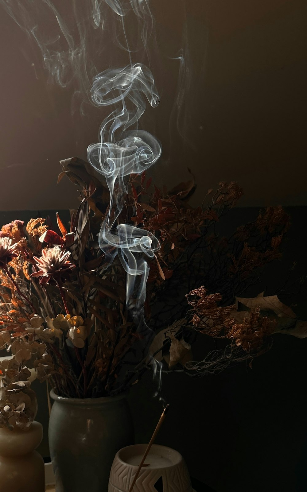 eine Vase gefüllt mit Blumen und Rauch auf einem Tisch