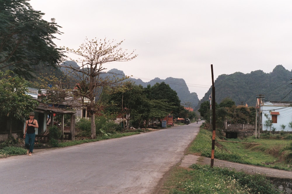 a man walking down a street in a rural area