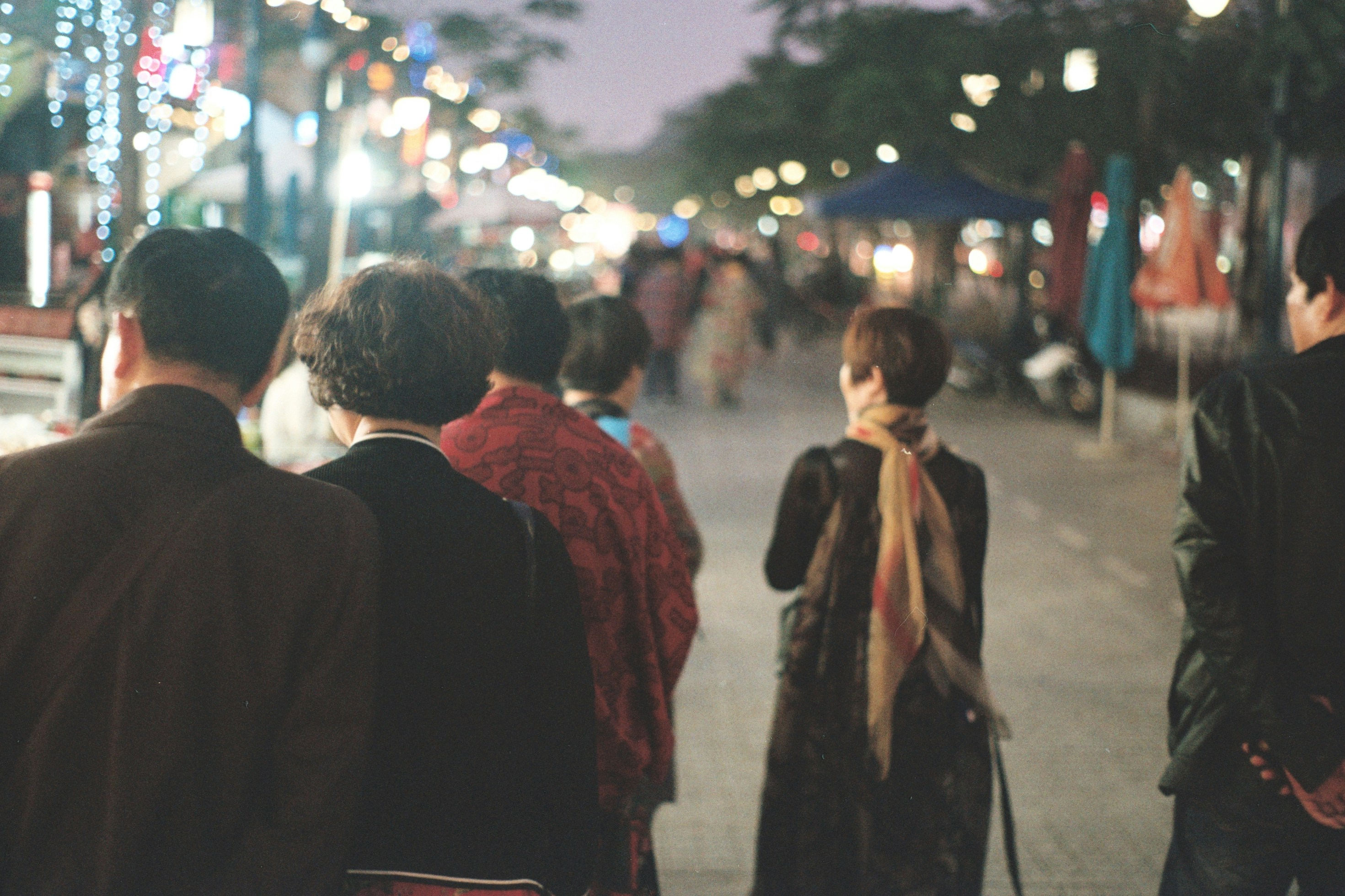 a group of people walking down a street at night