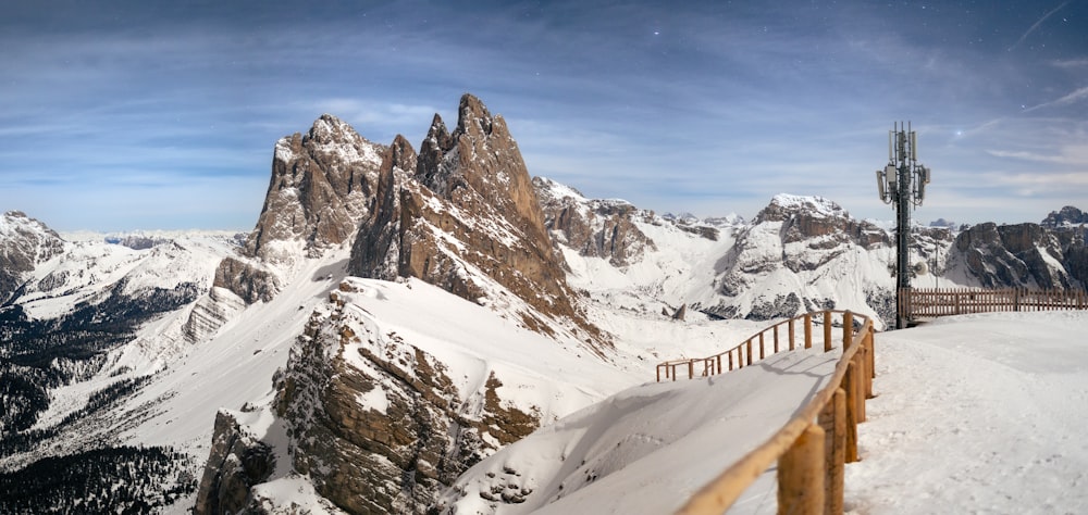 a snowy mountain range with a wooden fence