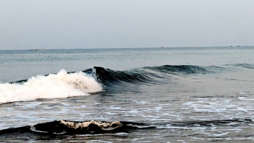 a large wave crashes into the shore of the ocean