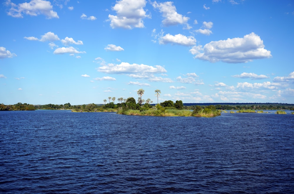 a body of water surrounded by trees and clouds