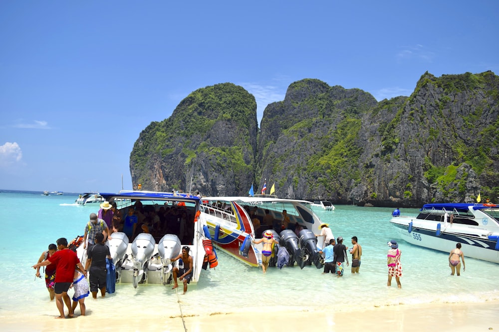 a group of people standing on a beach next to a boat