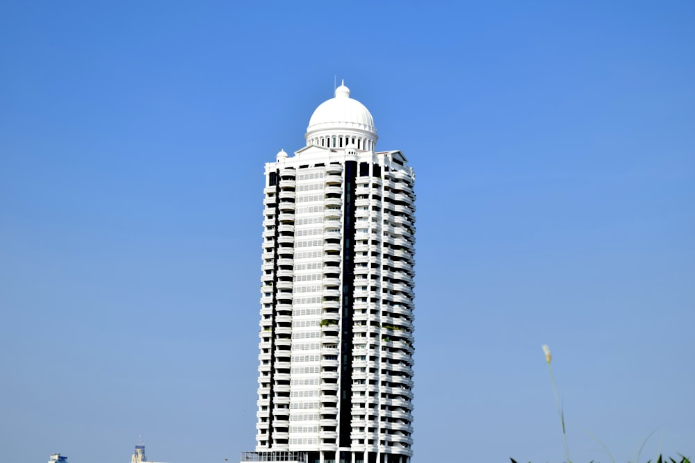 a tall white building sitting on top of a lush green field