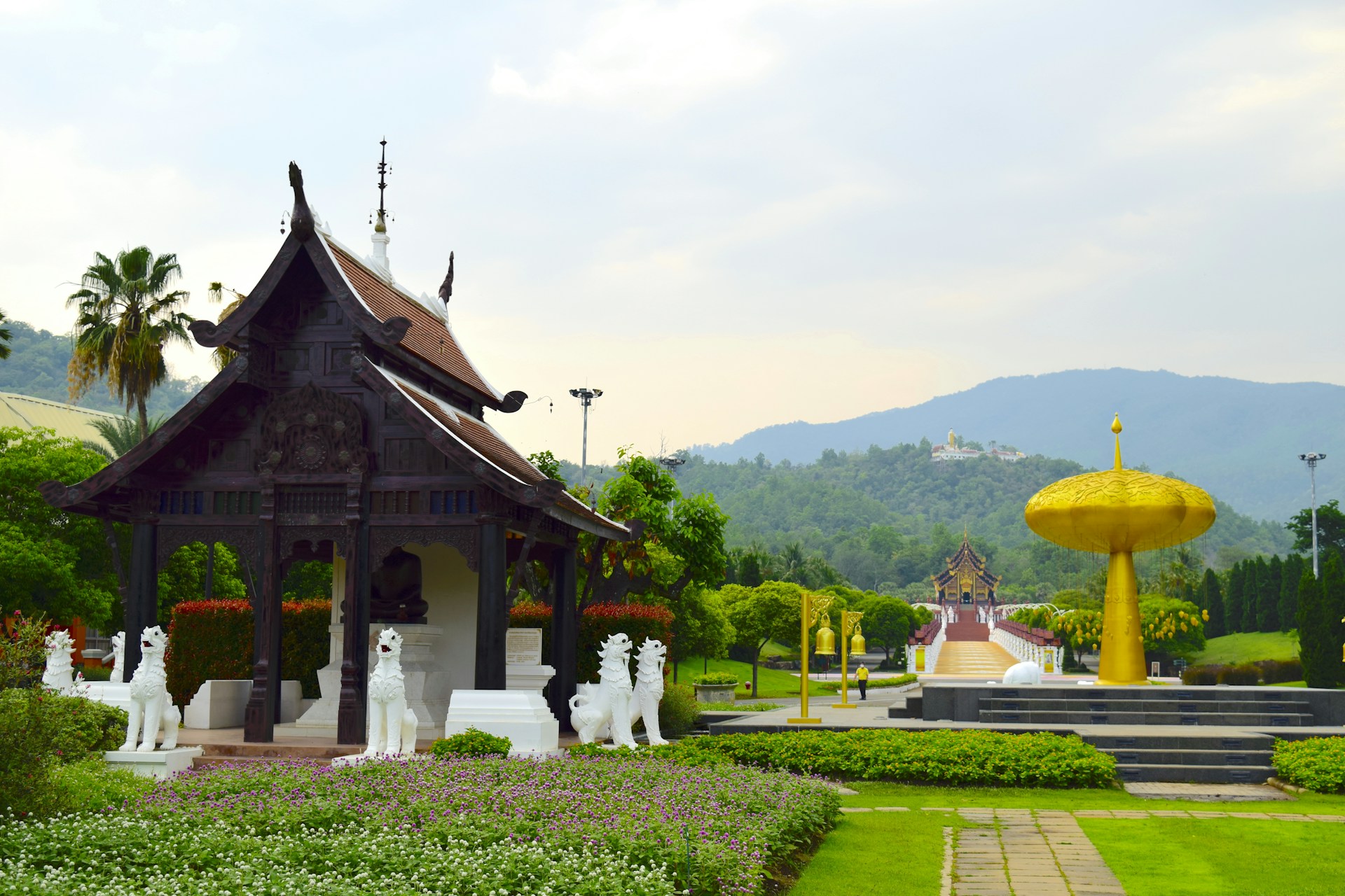 a gazebo in a garden with statues in the foreground