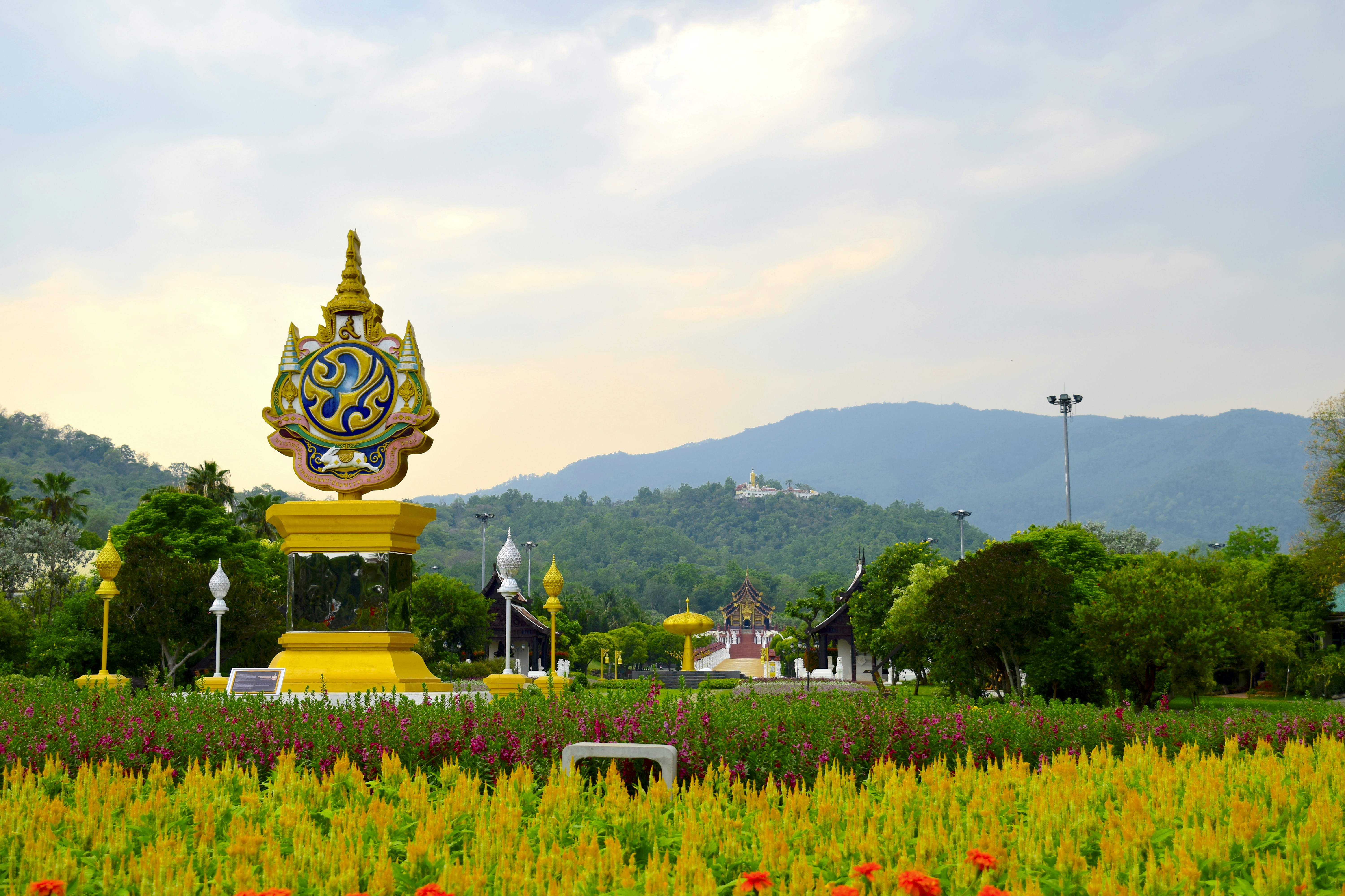 a large statue in the middle of a field of flowers