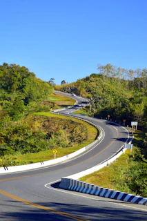 a curved road in the middle of a lush green hillside
