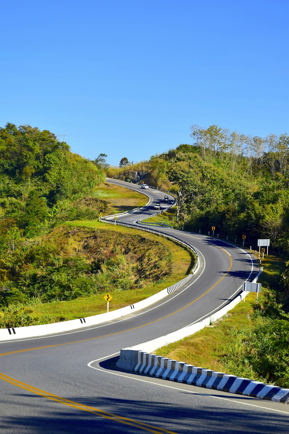 a curved road in the middle of a lush green hillside