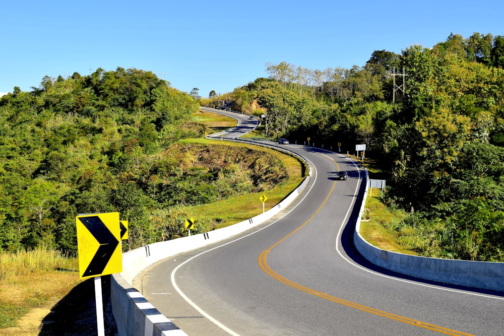 un virage sur la route avec un panneau jaune dessus